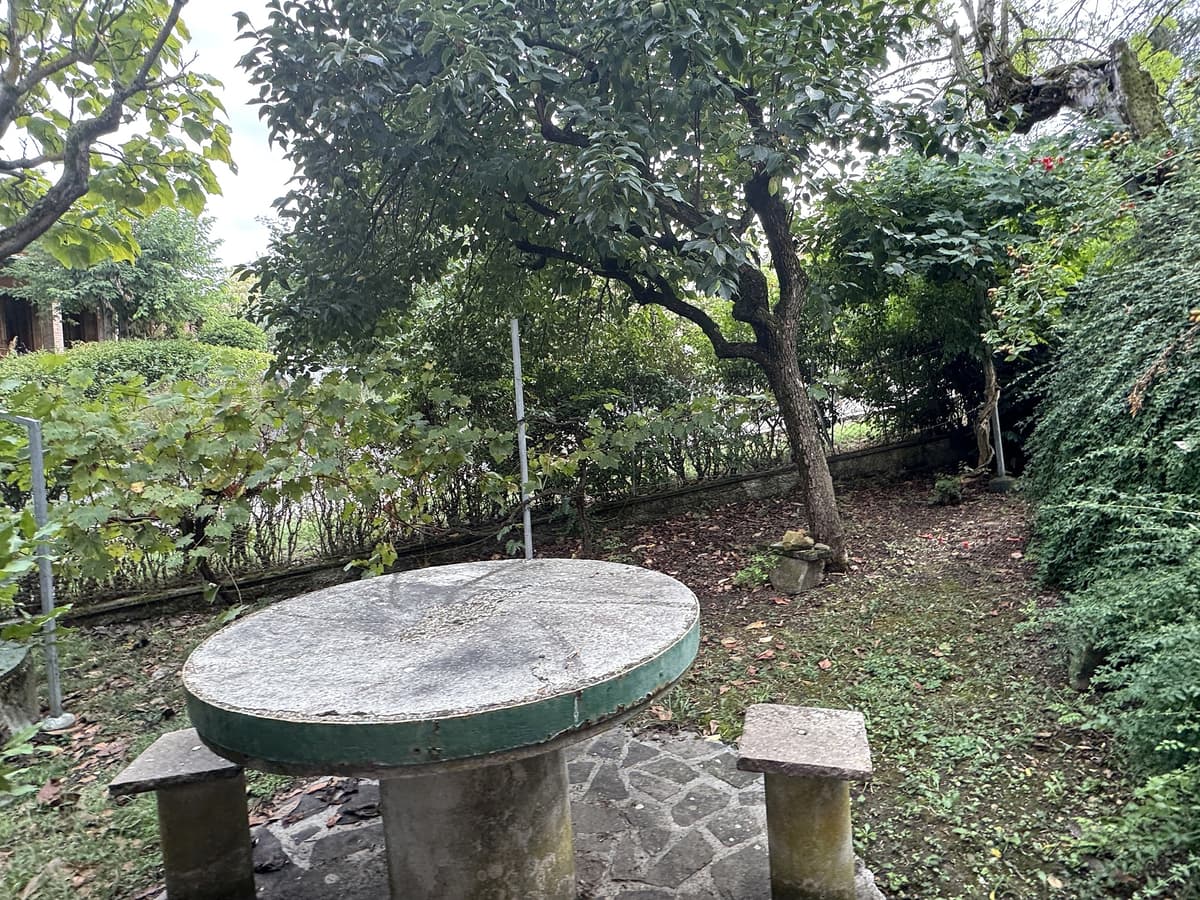 Tavolo in pietra con panchine — area relax nel giardino — Villa singola con giardino e vista sulla vallata a Montalto