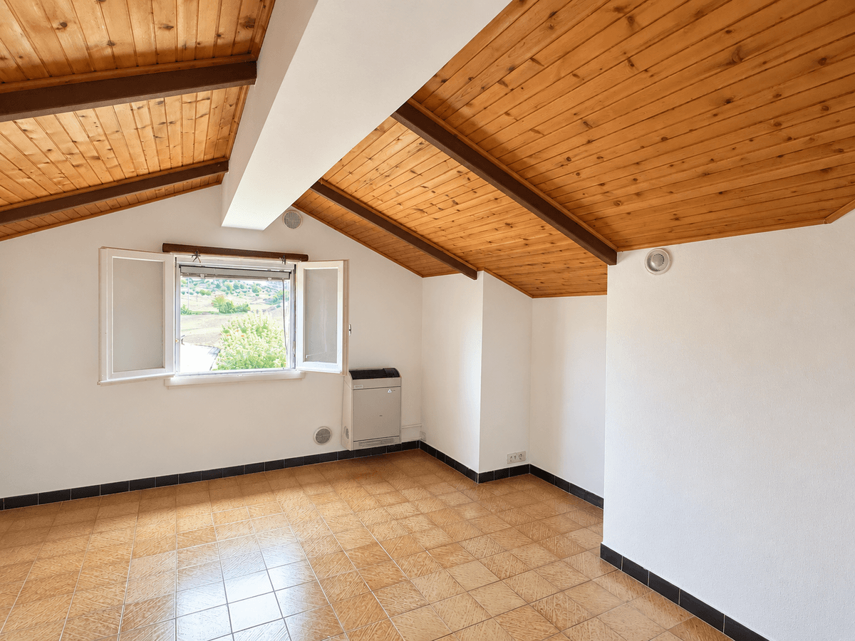 Camera mansarda — soffitto con travi in legno e pavimento in terracotta — Villa singola con giardino e vista sulla vallata a Montalto
